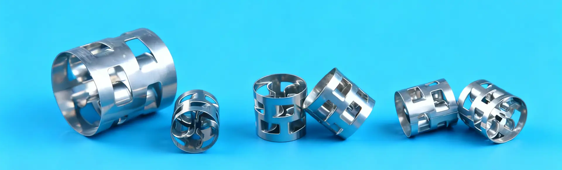 A large and two small metallic pall rings on the black glass.