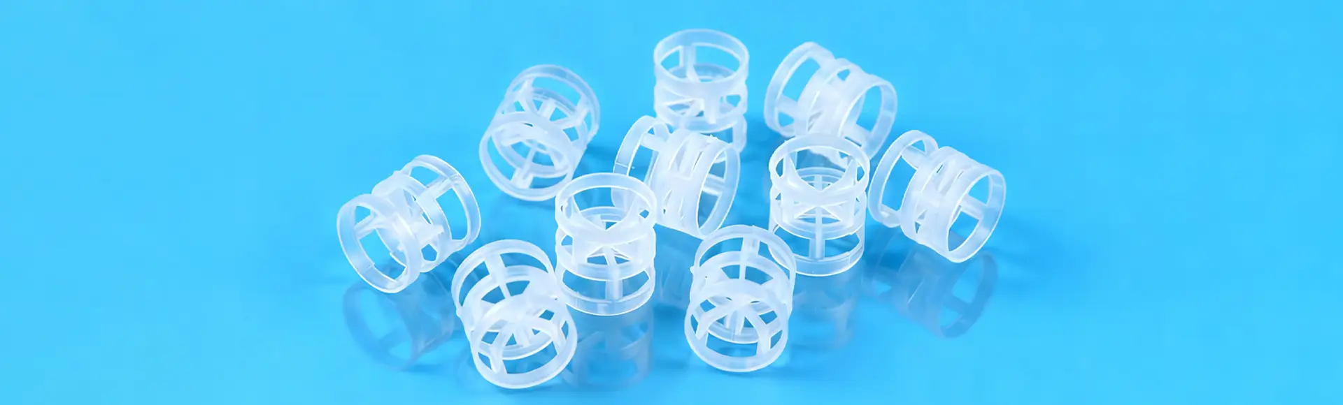 Several PP plastic pall rings are placed on the black glass in different conditions.