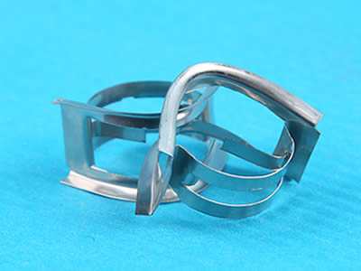 Two metal intalox saddles: one is standing on the blue background and the other is lean on the packing.